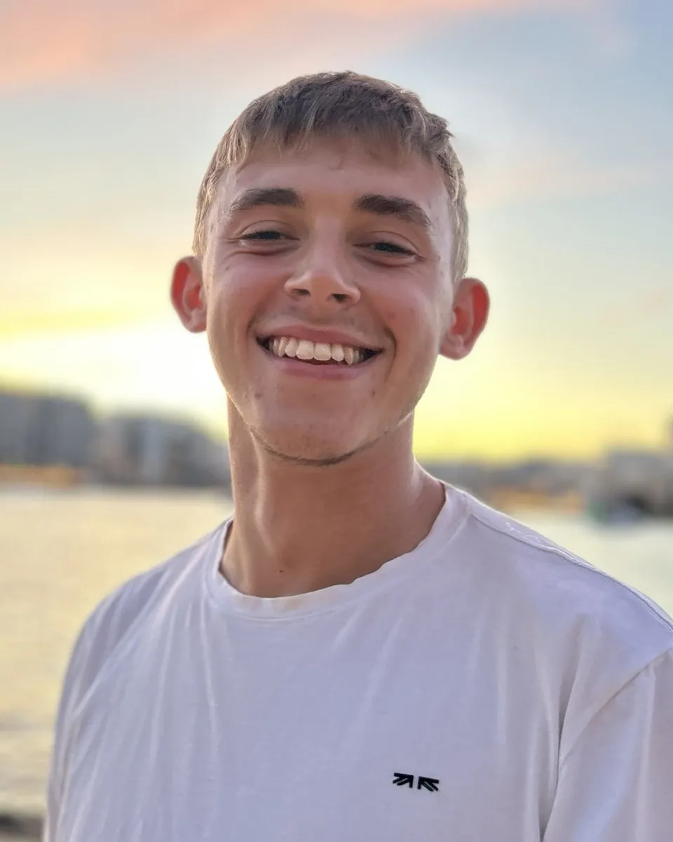 Callum Mckeown smiling by the sea at sunset